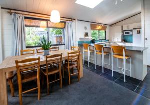 罗托鲁瓦Aura @ Home的厨房以及带木桌和椅子的用餐室。