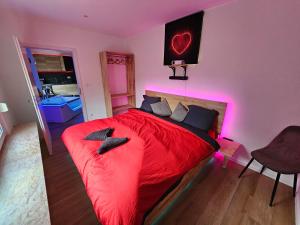 迪弗当日L'Appart Spa, Jacuzzi & Sauna的一间卧室配有红色的床和粉红色的灯
