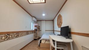 首尔Huesik Guesthouse的小房间设有一张床和一张带电脑的书桌