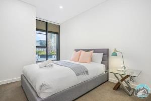 悉尼Aircabin - Zetland - Lovely - 2 Beds Apt Free Park的一间卧室配有一张床和一张玻璃桌
