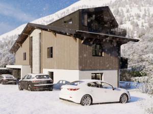 萨尔巴赫Bergzeit Apartments right on the ski slope的两辆汽车停在房子前面的雪地里