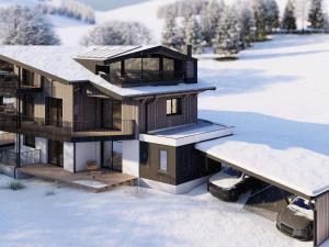 萨尔巴赫Bergzeit Apartments right on the ski slope的雪中的房子,地面上积雪