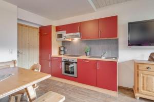 菲根Cosy apartment in F gen的厨房配有红色橱柜、水槽和桌子