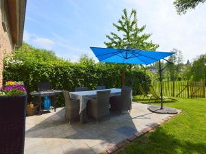 斯莱纳肯Stunning Holiday Home near Forest in Slenaken的露台上的一张带蓝伞的桌子
