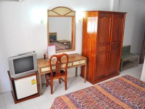 芭堤雅市中心海舞宾馆的一间卧室配有一张书桌、一台电视和一个梳妆台