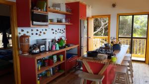 Ponta MalanganePequena Casa Holiday Home Malongane的一间厨房,里面设有红色的墙壁和一张桌子