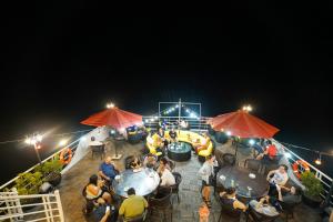 下龙湾Halong Dragon Bay Cruise的一群人晚上坐在甲板上的桌子上