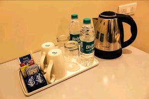 新德里Hotel HRS - New Delhi Railway Station的配有咖啡壶和瓶装水的柜台