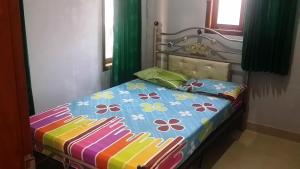 诗都阿佐SPOT ON 93880 Guest House Bu Iin Syariah的床上配有色彩缤纷的被子和枕头