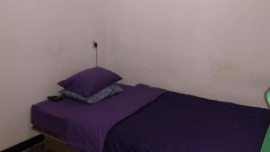 万隆OYO 93846 Gerlong Homestay的一张带紫色床单和枕头的床