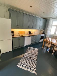 哈尔登Sentral og fargerik bygårdsleilighet的厨房配有绿色橱柜和桌椅