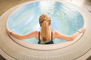 滨海迪沃Kyriad Prestige Residence & Spa Cabourg-Dives-sur-Mer的坐在圆形游泳池中的女人