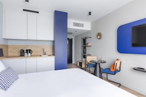 鲁瓦西昂法兰西Appart'City Collection Paris Roissy CDG Airport的卧室配有白色的床和蓝色的墙壁