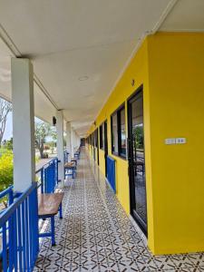 Ban KoYungthong Baan Suan Resort的黄色的蓝色建筑,上面有长椅