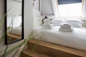 登博斯The Guest Apartments - Lange Putstraat的一间卧室配有一张带白色枕头和镜子的床