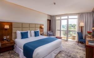 坎帕拉Golden Tulip Canaan Kampala的一间设有大床和窗户的酒店客房