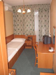 塔塔阿诺德酒店的小房间设有一张床和一张带电脑的书桌