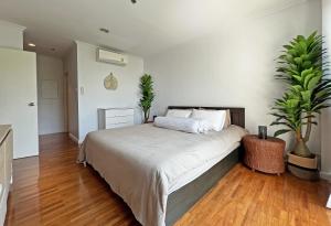 华欣2BR Beachfront Condo in central HuaHin, Baan Saen Ploen的一间卧室设有一张带两盆植物的大床