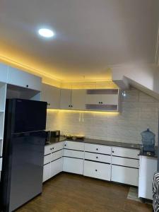 基加利Furnished House at Kibagabaga的厨房配有白色橱柜和黑色冰箱。