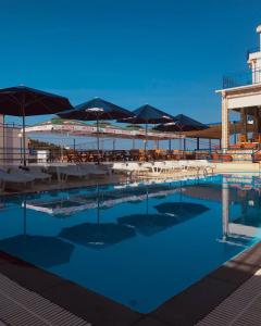 巴尔El Mar Hotel的一个带遮阳伞和桌椅的游泳池