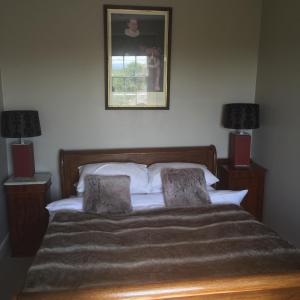 Hurst GreenIngram House with Hot Tub的一间卧室配有一张带两盏灯的床,墙上挂着一张照片