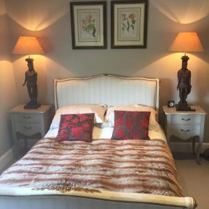 Hurst GreenIngram House with Hot Tub的一间卧室配有一张带两张桌子和两盏灯的床。