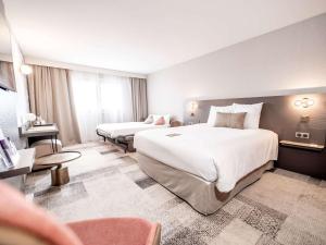 波尔多美居波尔多紫胶酒店的大型酒店客房设有两张床和一张书桌