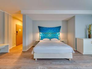 雷根斯堡雷根斯堡宜必思尚品酒店的一间卧室配有一张白色大床和蓝色床头板