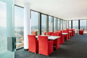 巴塞尔HYPERION Hotel Basel的一间设有红色椅子和桌子的用餐室以及窗户。