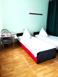 热舒夫Hostel Omega的配有一张桌子和一把椅子的客房内的两张床