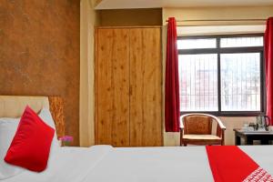 LukerganjOYO Flagship Bliss Inn的一间卧室配有一张带红色枕头的床和一扇窗户