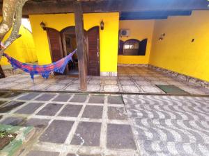阿拉亚尔-杜卡布Casa Praia Grande - Arraial do Cabo的黄色房子前面设有吊床