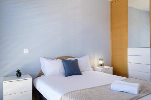 卡尼索GuestReady - Charming Caniço Retreat的卧室配有白色床和蓝色枕头