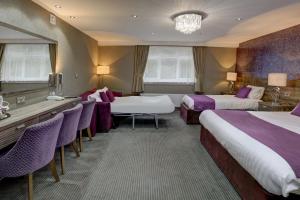 帕迪厄姆Burnley West Higher Trapp Hotel的酒店客房带两张床和一张桌子以及椅子。