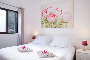 马希库GuestReady - Machico sea view residence - B的卧室配有一张白色床,墙上挂有绘画作品