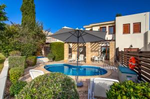 库克里亚2 bedroom Villa Kornos with private pool and golf views, Aphrodite Hills Resort的一座带遮阳伞的游泳池的房子