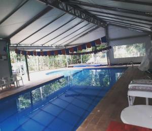 博西坎加Mandala casa 3 dorms cond fech piscina churrasqueira的大型游泳池设有屋顶,配有桌椅