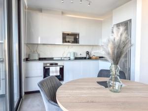 直布罗陀E1 Suites & Spa aparthotel style - Gym & Spa的厨房配有桌子和带羽毛的花瓶