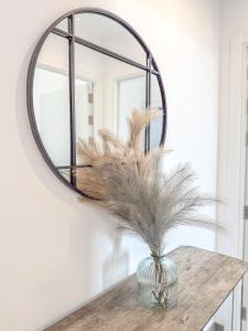 直布罗陀E1 Suites & Spa aparthotel style - Gym & Spa的墙上的圆镜子,带羽毛的花瓶