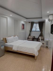 头顿An's Home Hotel Vũng Tàu的卧室配有一张白色大床和一张书桌