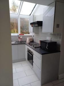 克利夫登Clifden Glen Cottage的厨房配有白色橱柜和黑色台面