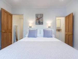 伦敦Charming Period Home near Surbiton with Garden的卧室配有带蓝色枕头的大型白色床