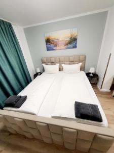 维斯马潘森奥普斯特尔酒店的卧室里一张大白色的床,配有绿色窗帘