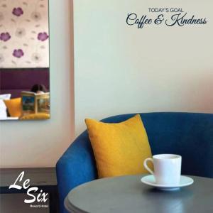 拜特龙Le Six Hotel And Resort的坐在蓝椅旁边的桌子上,坐在咖啡杯上