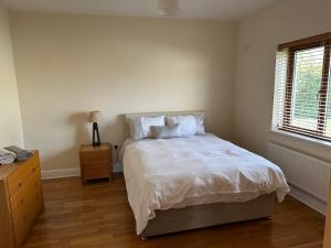 RooskeyHome near the River Shannon的一间卧室配有一张带白色床单的床和一扇窗户。