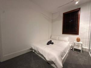 悉尼Remarkable 2 Bedroom House at the Centre of Darlinghurst的一间白色卧室,床上有黑色的袋子