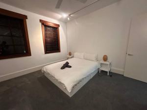 悉尼Remarkable 2 Bedroom House at the Centre of Darlinghurst的卧室配有白色的床和帽子