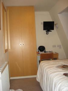 伦敦美洲大酒店的一间卧室配有衣柜、一张床和一台电视机