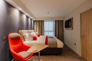 利物浦Holiday Inn Express Liverpool - Central, an IHG Hotel的酒店客房,配有一张床和一张红色椅子