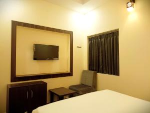 埃尔加德R Hotels By Suraj Residency Yercaud的一间卧室配有一张床、一把椅子和镜子
